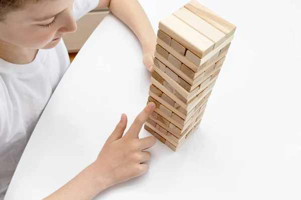A preteen caucasian boy playing wooden block tower board game for practicing his physical and mental skill and entertainment