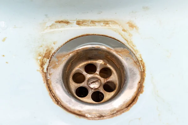 Maille de vidange d'évier sale, trou avec échelle de calcaire ou de chaux et rouille dessus gros plan, lavabo de salle de bain sale rouillé — Photo