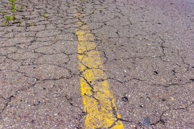Sarı düz çizgi ile eski çatlak yol asfalt, terk edilmiş büyümüş yolda grunge işaretleme