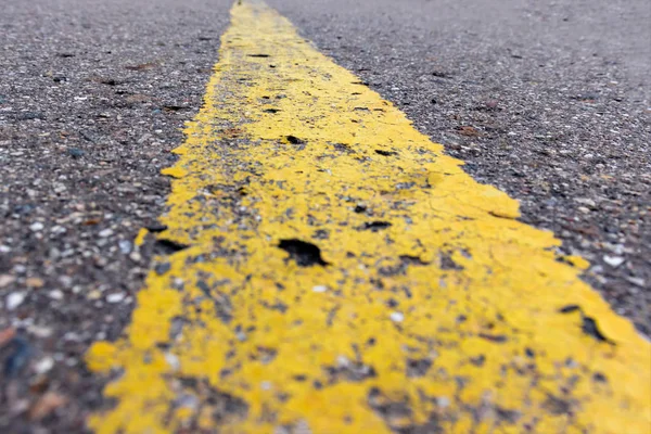 Yellow solid line, grunge single road marking on asphalt close up, background with copy space — Stock Photo, Image