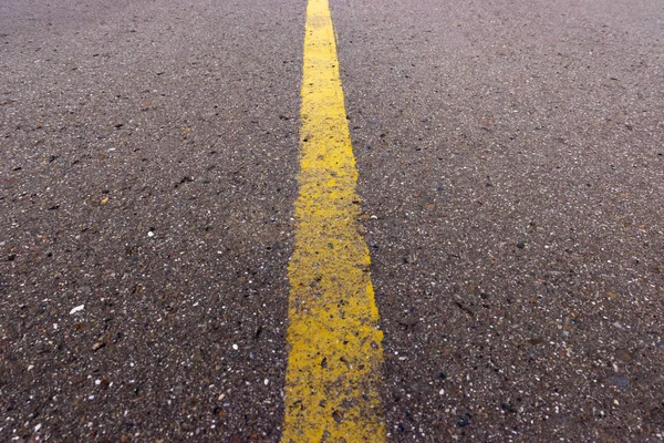 Yellow solid line, grunge single road marking on asphalt, background with copy space — Stock Photo, Image