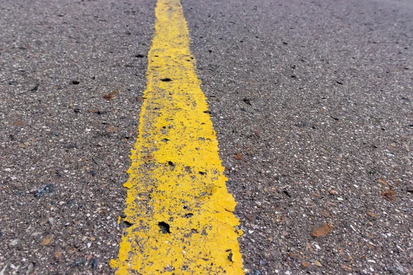 Yellow solid line, grunge single road marking on asphalt, background with copy space — Stock Photo, Image
