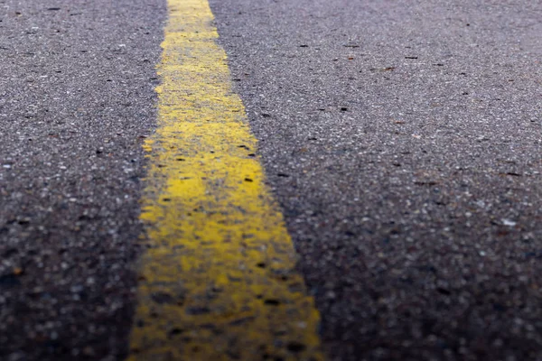 Yellow solid line, grunge single road marking on asphalt, background with copy space — Stock Photo, Image