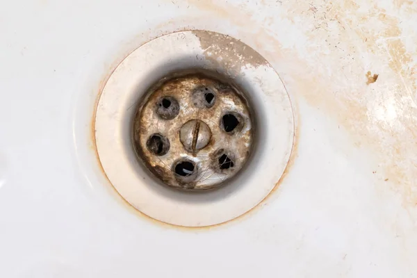 Dirty sink drain mesh, hole with limescale or lime scale and rust on it close up, dirty rusty bathroom washbowl