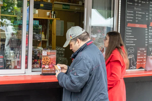 MOSCÚ, RUSIA - 02 de agosto de 2019: Una pareja que compra comida rápida en la calle en el puesto durante el paseo en un parque de la ciudad en verano, comiendo comida rápida sobre la marcha y el concepto de comida para llevar — Foto de Stock
