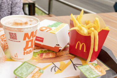 Moskova, Rusya - 02 Ağustos 2019: Macdonalds fast food restoranında bir masada tepside dağınık lıkta yatan hamburgerler, patates kızartması, külçeler ve alkolsüz içecek, abur cubur konsepti