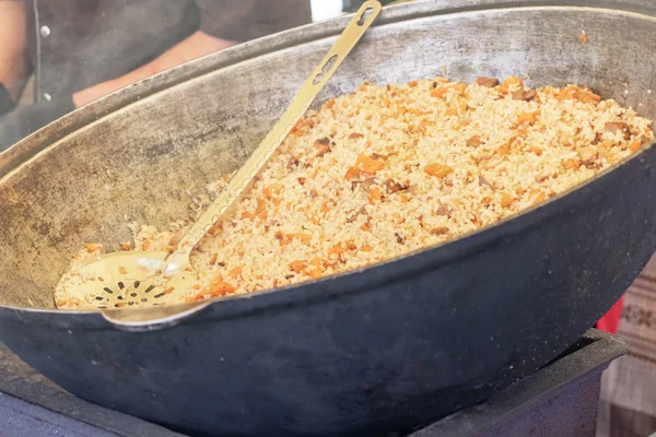 Cooking original Uzbek pilaf in big wok on open fire, street food for take out — Stock Image Cooking original Uzbek pilaf in big wok on open fire, street food for take out Stock Photo