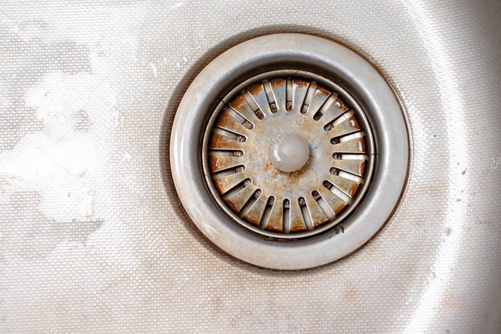 Old rusty calcified drain hole in the kitchen sink with limescale and scurf scum, copy space