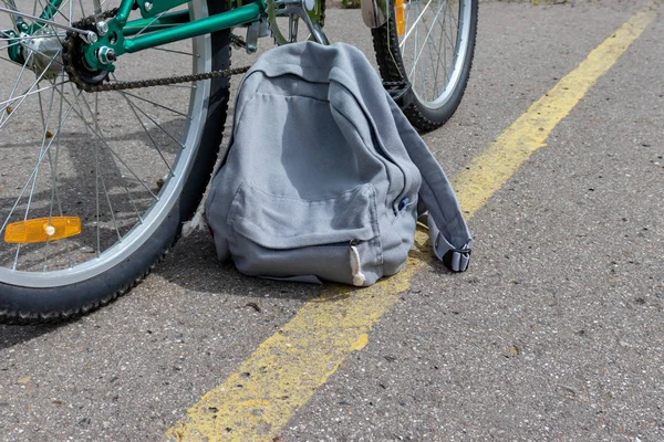 Велосипед и серый рюкзак, стоящий на асфальтированной дороге с желтой линией дорожной разметки, концепция велосипедного путешествия — стоковое фото