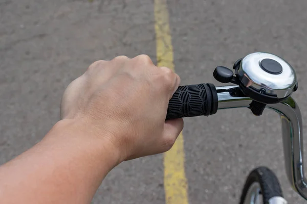 Female hand holding a bicycle handlebar and riding a bike on a road with yellow marking, bicycle travelling and journey