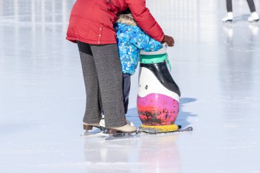 Moskova, Rusya- 02 Mart 2019: Çocuğuna kış patenpistinde paten yapmayı öğreten kadın, noel tatillerinde ve tatillerinde aile eğlencesi ve spor aktivitesi