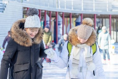 Moskova, Rusya- 02 Mart 2019: Kışlık buz pateni pistinde kışlık kıyafet, noel tatili ve tatillerinde aile eğlencesi ve spor aktivitesi giyen iki mutlu kadın