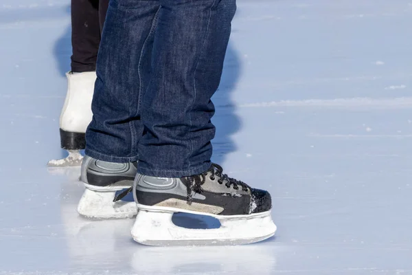 Ice skating, woman and a man, couple legs wearing white leather and black skates, training on a frosen snowy skating rink in winter close up