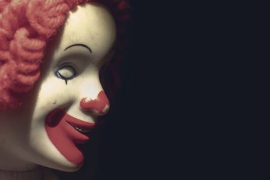 Korkunç, şeytani, sinsi bir palyaço yüzü. Ürkütücü bir gülümsemesi var. Siyah arka planda fotokopi alanı, koulrofobi ve korkuları var.