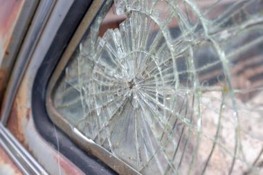 Eski paslı bir arabanın kırık cam penceresi