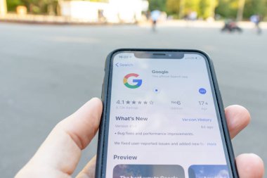 Moskova, Rusya - 01 Eylül 2019: Ekranda google uygulama simgesi olan bir akıllı telefon el tutuyor. Oyun pazarında Google uygulama simgesi, arka planda şehir parkı
