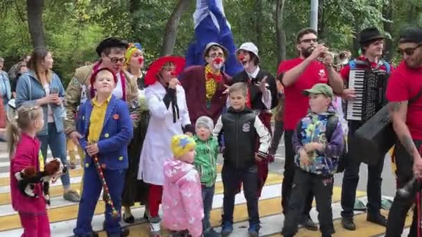 Moscú, Rusia - 14 de septiembre de 2019: Festival de payasos en la ciudad, payasos con ropa colorida y con un maquillaje brillante y músicos callejeros se comunican con los niños y hacen caras divertidas — Vídeos de Stock