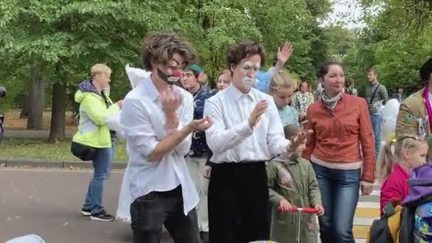 俄罗斯莫斯科 - 2019年9月14日：小丑节在城市，小丑在五颜六色的衣服和明亮的化妆显示一个哑剧和搞笑的脸 — 图库视频影像