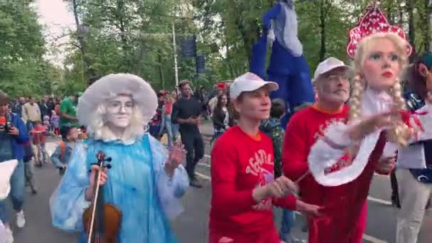 Moskva, Rusland - 14. september 2019: Klovnefestival i byen, klovne i farverigt tøj og med en lys makeup og gademusikere parade langs gaden og lave sjove ansigter – Stock-video