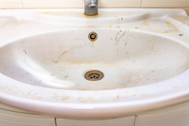 Pas lekeleri, kireç boyası ve banyoda musluğu olan eski kirli lavabo, su musluğu.