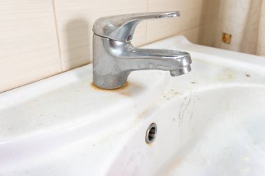 Pas lekeleri, kireç boyası ve banyoda musluğu olan eski kirli lavabo, su musluğu.