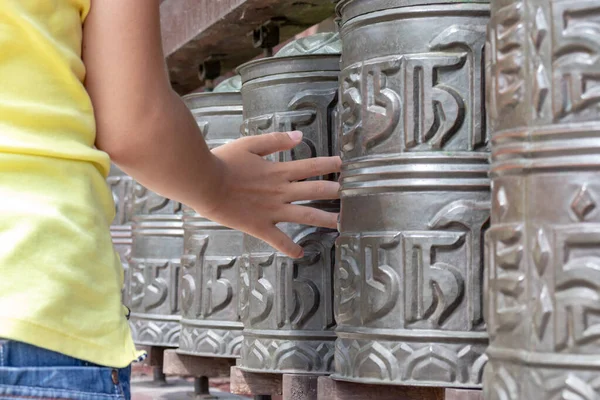Людська рука торкається, обертається непальськими традиційними металевими молитовними колесами, що звисають поспіль — стокове фото