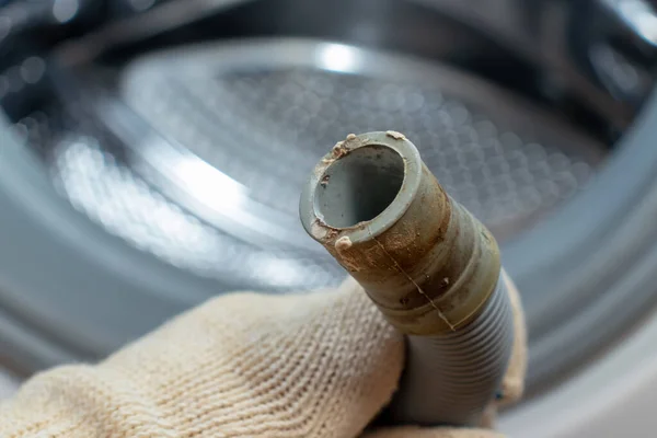 Mano di un idraulico che tiene un tubo flessibile rotto di scarico della lavatrice, intasato e coperto con scala di calce, calcare sporco e ruggine — Foto Stock