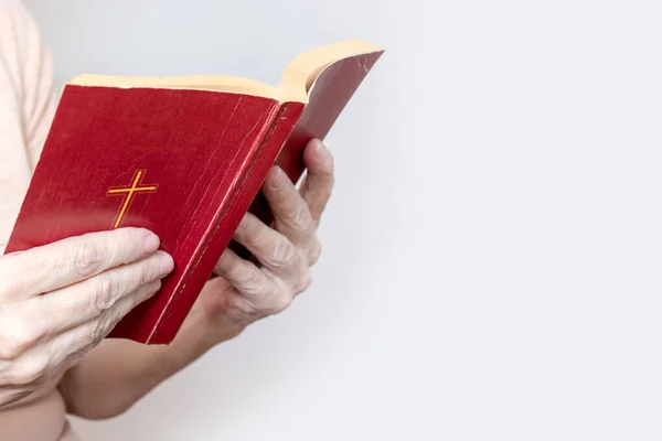 Mujer mayor sosteniendo una antigua Biblia en las manos, anciana sosteniendo el Nuevo Testamento y orando, espacio para copiar — Foto de Stock