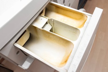 Kirli, küflü çamaşır makinesi deterjanı ve kumaş kremi kutusunun çekmecesini kapat. Küf, pas ve kireç rengi çamaşır makinesi tepsisi. Ev aletleri periyodik bakım