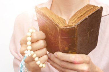 Genç dua eden Hıristiyan bir kadının ellerinde tespih ve kutsal bir incille.