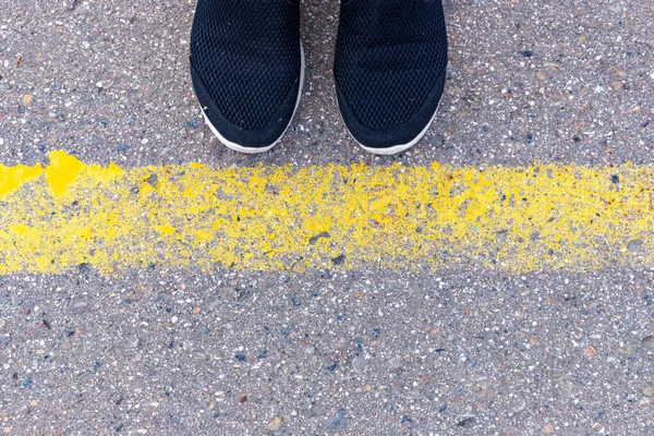 Sneakers på asfalterad väg med gul linje vägmarkering, ovanifrån — Stockfoto