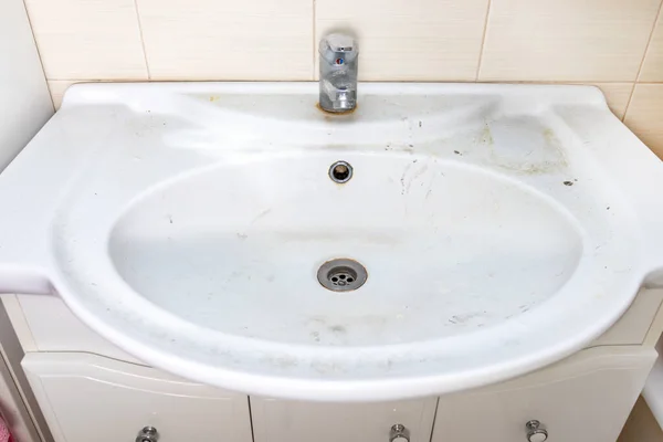 Старий брудний умивальник з іржавими плямами, вапняками та мильними плямами у ванній кімнаті з краном, водяним краном — стокове фото