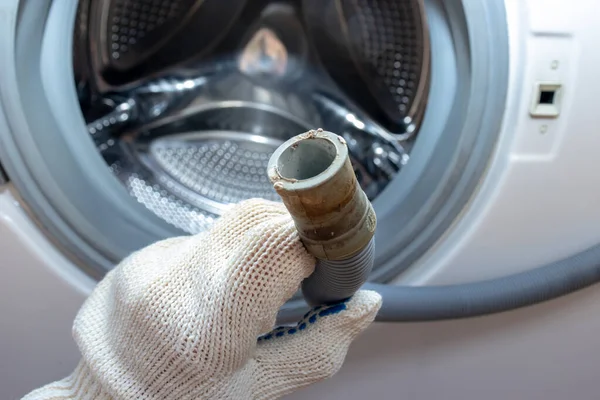 Mão de um encanador segurando uma mangueira de drenagem flexível quebrada da máquina de lavar roupa, entupida e coberta com escala de cal, escala de tempo de sujeira e ferrugem — Fotografia de Stock