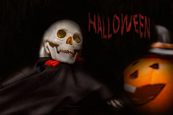 Tarjeta de Halloween con esqueleto espeluznante y calabaza naranja sobre fondo oscuro —  Fotos de Stock