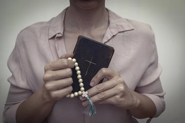 Young praying christian woman\'s hands with a rosary and holy bible