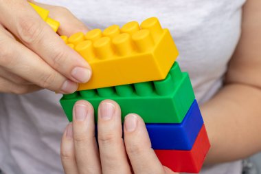 Renkli oyuncak plastik tuğlalardan inşa edilen eller, beyaz arka plan üzerine inşa edilen bloklar