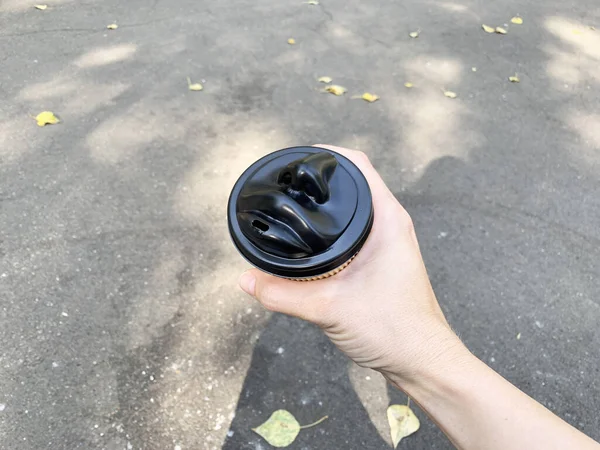 Рука держит одноразовую бумажную чашку кофе с черным человеческим лицом в форме чашки — стоковое фото