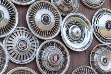 Moscow, Russia - August 11, 2019: Wall collection of vintage rusty automobile hubcaps of retro cars clipart
