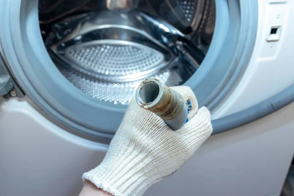 Hand of a plumber holding a broken flexible drain hose of washing machine, clogged and covered with lime scale, dirt limescale and rust — Stock Photo, Image