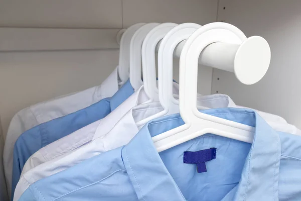 Blue and white classic man's shirts on hangers in a wardrobe — Stock Photo, Image