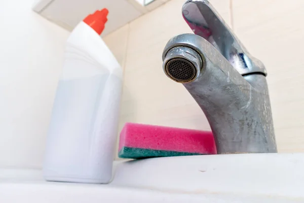 Cleaning products, agents and sponge for washing dirty faucet with limescale, calcified water tap with lime scale on washbowl in bathroom