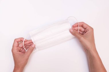 Beyaz arka planda beyaz koruyucu cerrahi yüz maskesi tutan eller, epidemi sırasında PPE kişisel koruma..