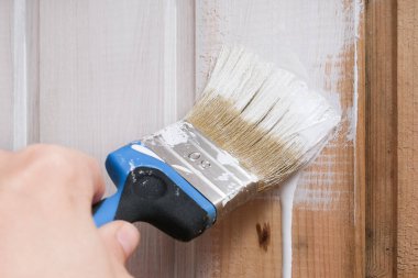 Beyaz akrilik boyalı bir el fırçası ahşap bir duvardan aşağı süzülüyor, ev onarımı, inşaat ve diy, ahşap işleme ve tedavi