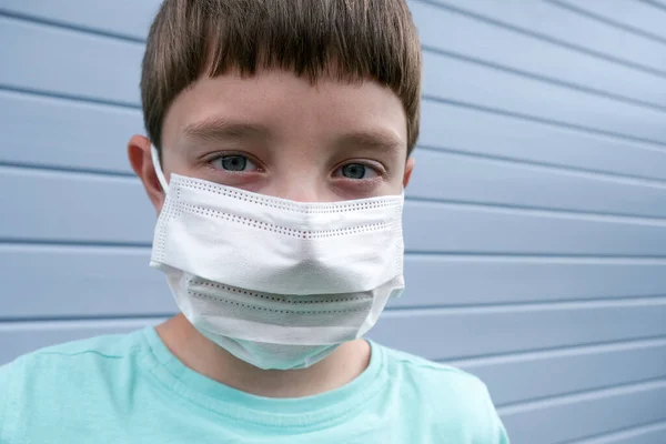 Un niño con máscara médica quirúrgica blanca protectora para prevenir infecciones durante la epidemia —  Fotos de Stock