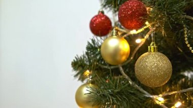 Kırmızı ve altın tatil toplarıyla süslenmiş Noel ağacı, bir elektrik çelengi parıldıyor ve yanıp sönüyor, yeni yıl ve yeni yıl geleneği beyaz arka planda fotokopi alanı ile