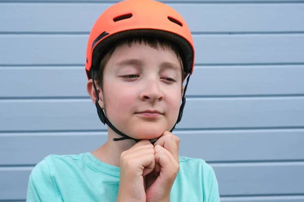 Retrato de adolescente caucásico chico abotonamiento naranja deporte accidente casco, aprender a montar en bicicleta o monopatín en verano, seguridad y protección mientras los niños al aire libre actividad — Foto de Stock