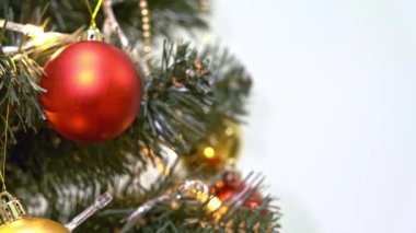 Kırmızı ve altın tatil toplarıyla süslenmiş Noel ağacı, bir elektrik çelengi parıldıyor ve yanıp sönüyor, yeni yıl ve yeni yıl geleneği beyaz arka planda fotokopi alanı ile