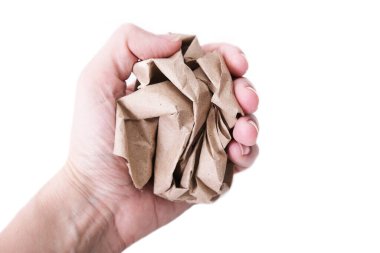 A hand clenched into a fist holding crushed, crumpled sheet of brown craft recycled paper isolated on white, recycling or fail creativity concept clipart