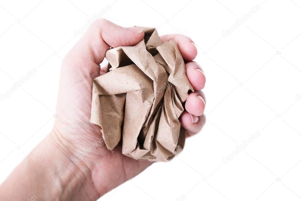 A hand clenched into a fist holding crushed, crumpled sheet of brown craft recycled paper isolated on white, recycling or fail creativity concept