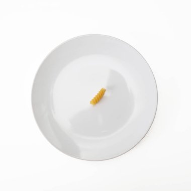 Beyaz seramik tabakta çiğ fusilli makarna. Akdeniz diyet konseptini inceltiyor.